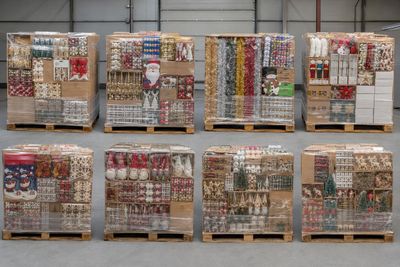 Plusieurs palettes contenant des articles variés sont empilées dans un entrepôt.