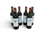 quatre bouteilles de vin sont alignées sur une surface blanche