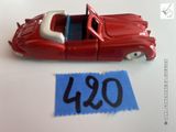 une petite voiture rouge posée à côté d'une feuille de papier bleue