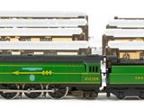 a green and black train on the tracks next to a building