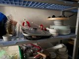 shelves filled with dishes and utensils in a cluttered kitchen