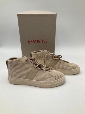 Les chaussures sont beiges et sont ornées d'une chaîne.