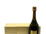 bottle of champagne next to a box of chocolates on a white surface