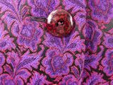 a button that is on a purple and black fabric