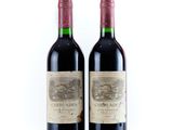 two bottles of red wine sitting next to each other on a white surface