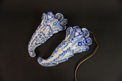 une paire de chaussures en porcelaine bleue et blanche posées sur un fond noir
