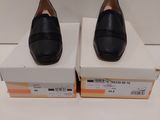 Deux paires de chaussures noires sont posées sur une boîte.