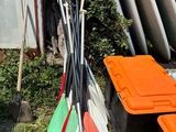 a pile of surfboards and paddles sitting on the grass