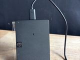 un petit appareil noir branché à un chargeur posé sur une table