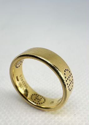 gros plan d'une bague en or sur une surface blanche