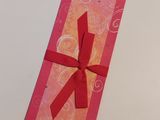 boîte-cadeau rose et orange ornée d'un ruban rouge sur un fond blanc