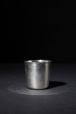 a close up of a metal cup on a table with a black background