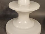a white candle holder with a white candle on it