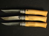 three knives are lined up on a black surface with a wooden handle