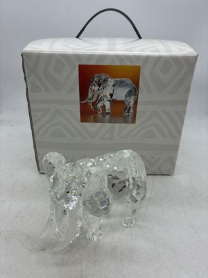 une figurine d'éléphant dans une boîte, posée sur une surface blanche