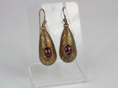 pair of gold tone earrings with garnets on clear acrylic stand