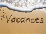 le mot « vacanes » écrit dans le sable sur la plage