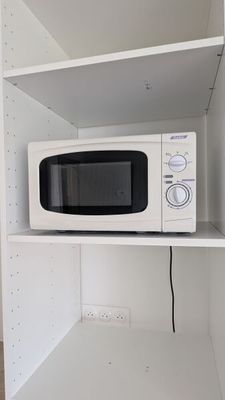 un micro-ondes posé sur une étagère dans un coin de la pièce