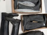 Plusieurs paires de bottes noires se trouvent dans une boîte posée sur une table