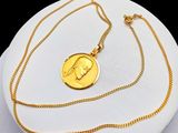 necklace with a gold coin on a white plate on a black background