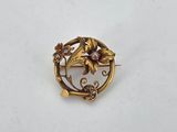 an image of a gold brooch with flowers and leaves on it