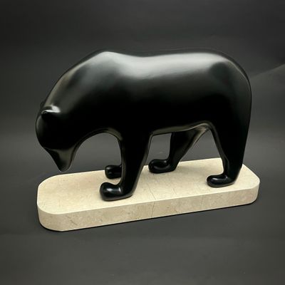 sculpture représentant un ours noir posée sur un socle en marbre, sur fond noir