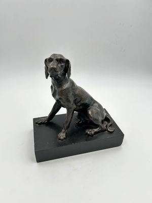 une statue représentant un chien assis sur un socle noir