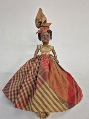 a close up of a doll wearing a dress and hat
