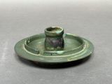 une petite assiette verte sur laquelle est posé un bougeoir