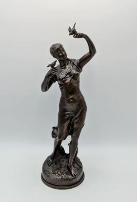 bronze statue of a woman holding a bird on a pedestal