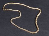 gros plan d'un collier en or sur une surface noire