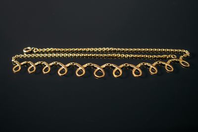 gros plan d'un bracelet en chaîne en or sur fond noir