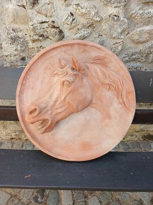 une assiette ornée d'une tête de cheval, posée sur un banc
