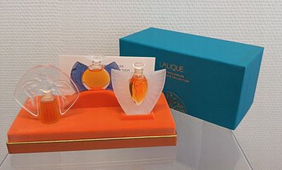 deux flacons de parfum posés sur une boîte orange