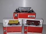 four toy trains sitting on top of boxes on a white surface