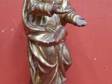 statue en or représentant une femme tenant une croix, posée sur un fond rouge
