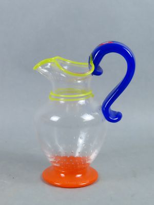 a glass pitcher with a blue handle and a yellow handle