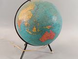 un petit globe posé sur un socle, sur une surface blanche