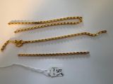 a close up of three gold chains on a white surface