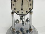 a silver clock on a silver stand with a white background