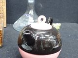 a black and pink vase and a glass bottle on a table