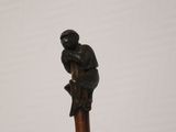 an image of a statue of a man sitting on top of a wooden stick