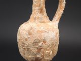 an old vase with a handle is on a clear stand
