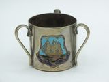 a silver cup with a ship on it on a white surface