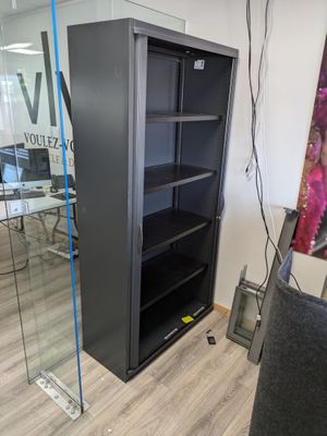 a black bookcase with a glass door in a room