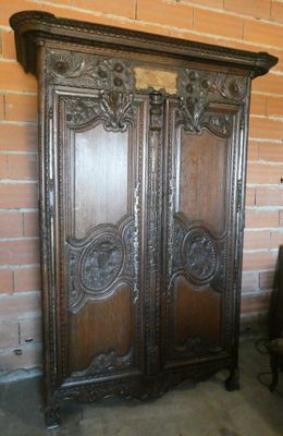 une vieille armoire en bois dans une pièce adossée à un mur de briques