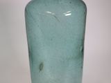 a green glass bottle that is sitting on a table