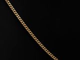 a gold necklace with a chain on a black background