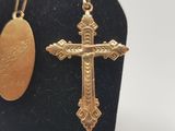 gold plated cross and oval pendant on a black stand
