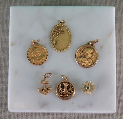 gold plated charms and pendants are displayed on a marble surface